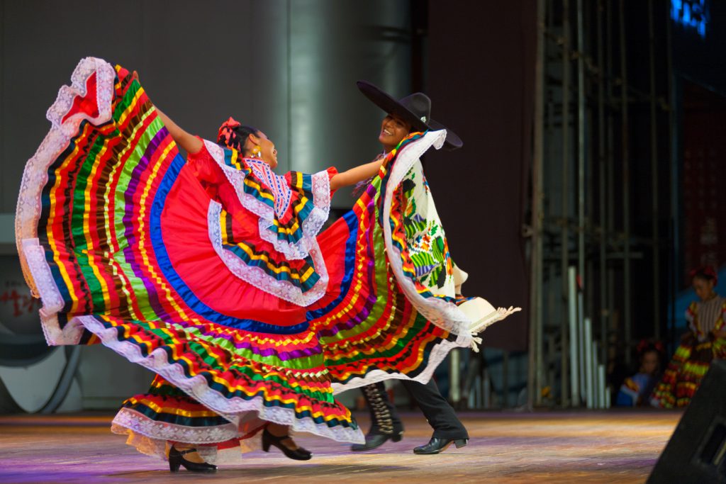 SEOUL KOREA - SEPTEMBER 30 2009: A traditional Mexican Jalisco dancer spreads her colorful red dress in front of her partner during a folk show at a public outdoor stage at city hall on September 30, 2009 at Seoul Korea