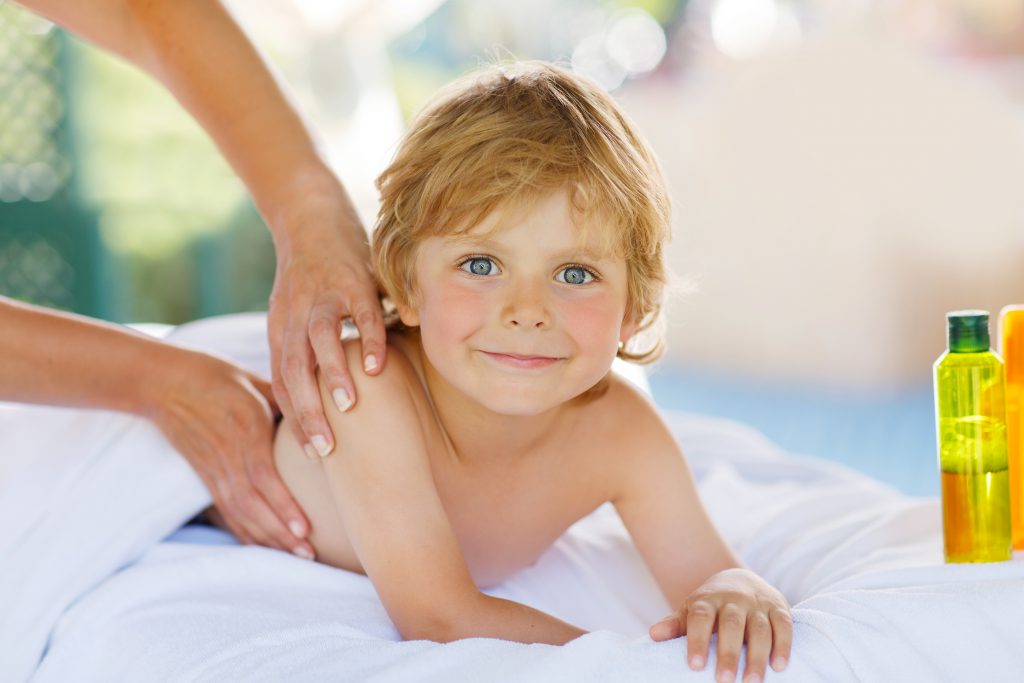 Adorable little blond kid relaxing in spa with having thai massage.